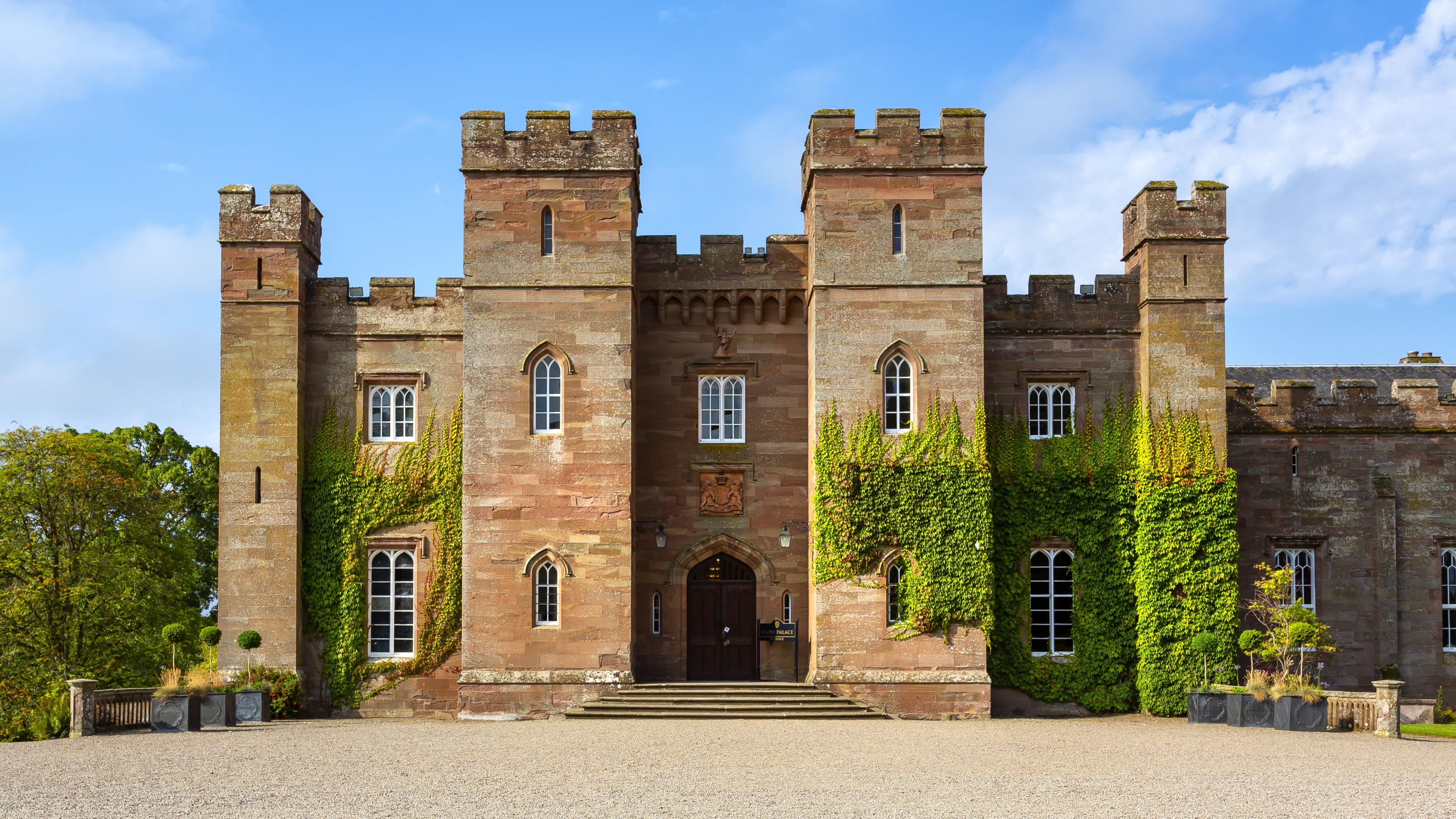Panoramaudsigt over det historiske Scone Palace i Perth, Skotland, med imponerende nygotisk rød sandstensarkitektur og efeudækkede mure