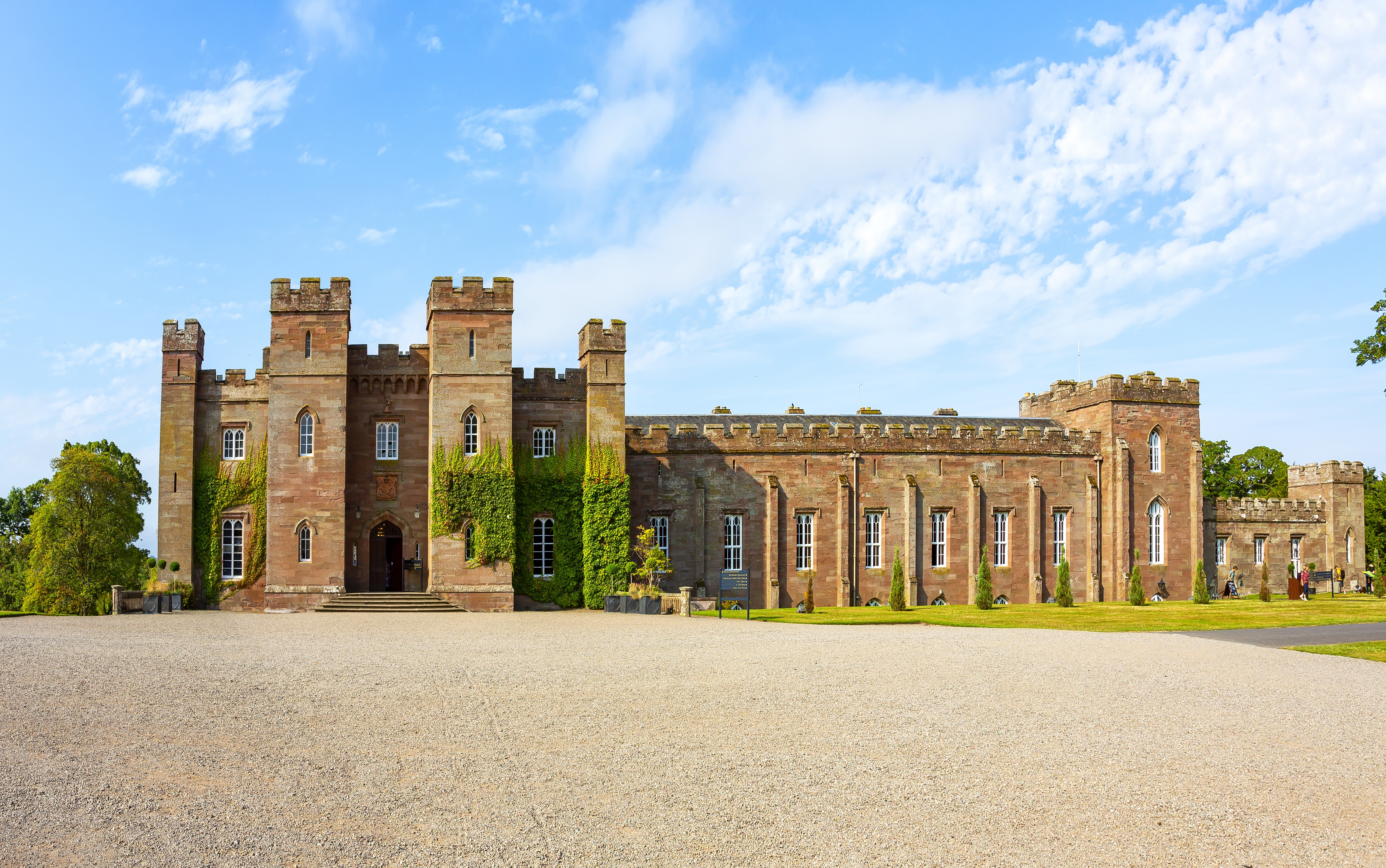 Panoramaudsigt over Scone Palace, et storslået neo-gotisk palads bygget i rødt sandsten nær Perth i Skotland, omgivet af grønne plæner