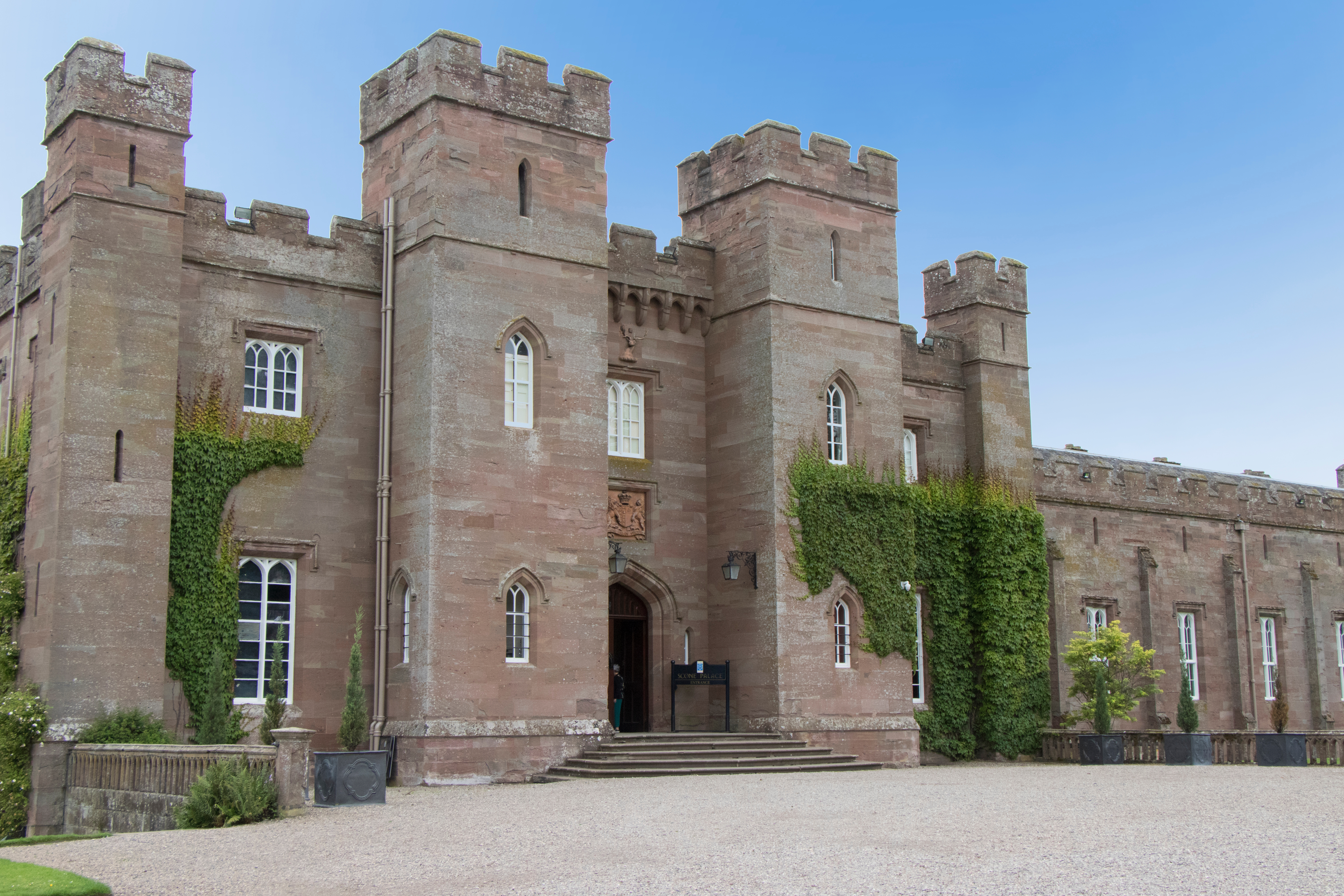 Historiske Scone Palace i Perthshire, Skotland, med middelalderlige sandstenstårne og efeuklædte mure på en solrig dag