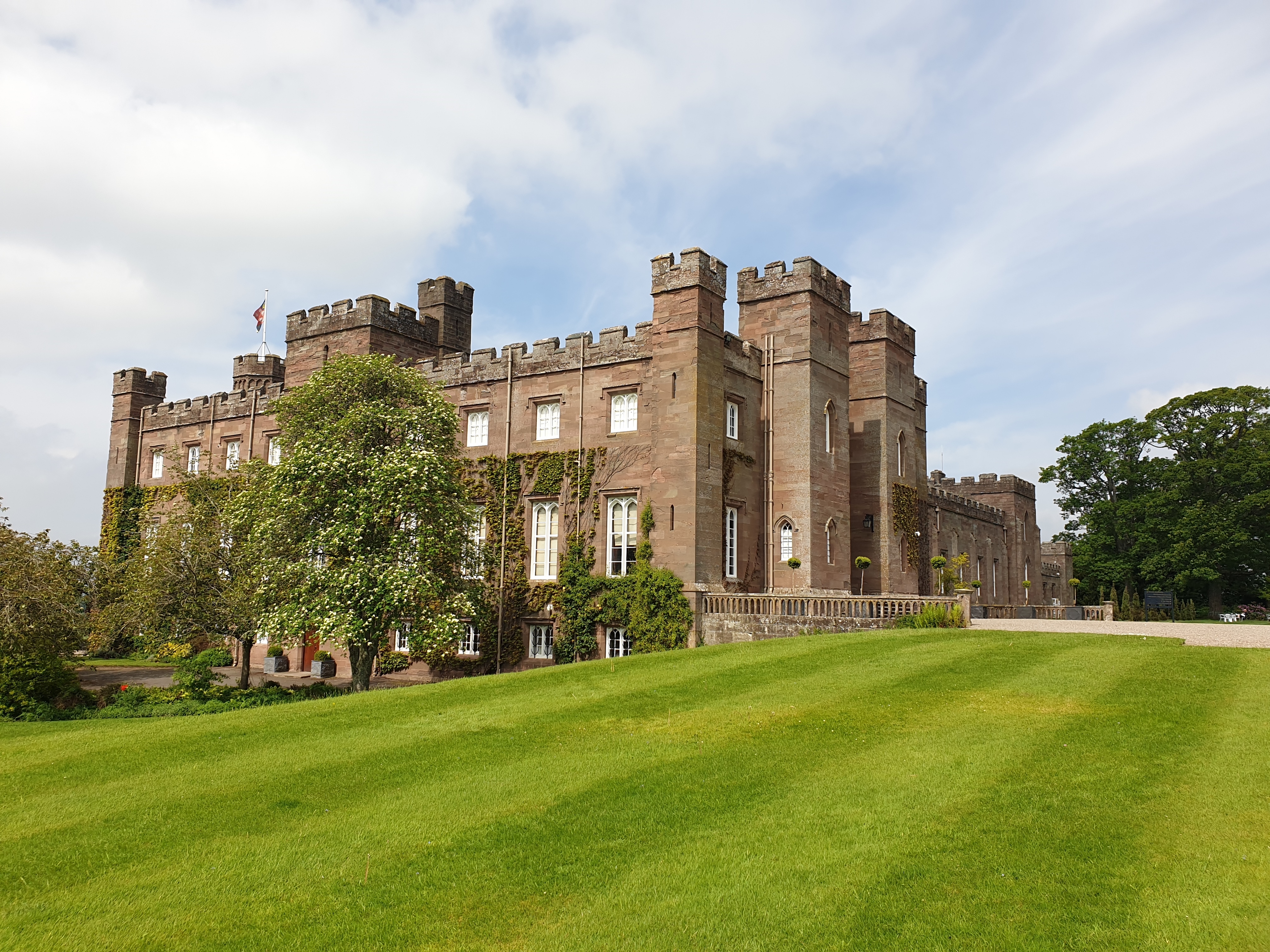 Scone Palace i Skotland med smukke røde sandstenstårne og grønne plæner foran det historiske slot i Perthshire