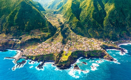 Betagende luftfoto af den idylliske kystby Seixal på Madeira, hvor frodige grønne bjerge møder det azurblå Atlanterhav
