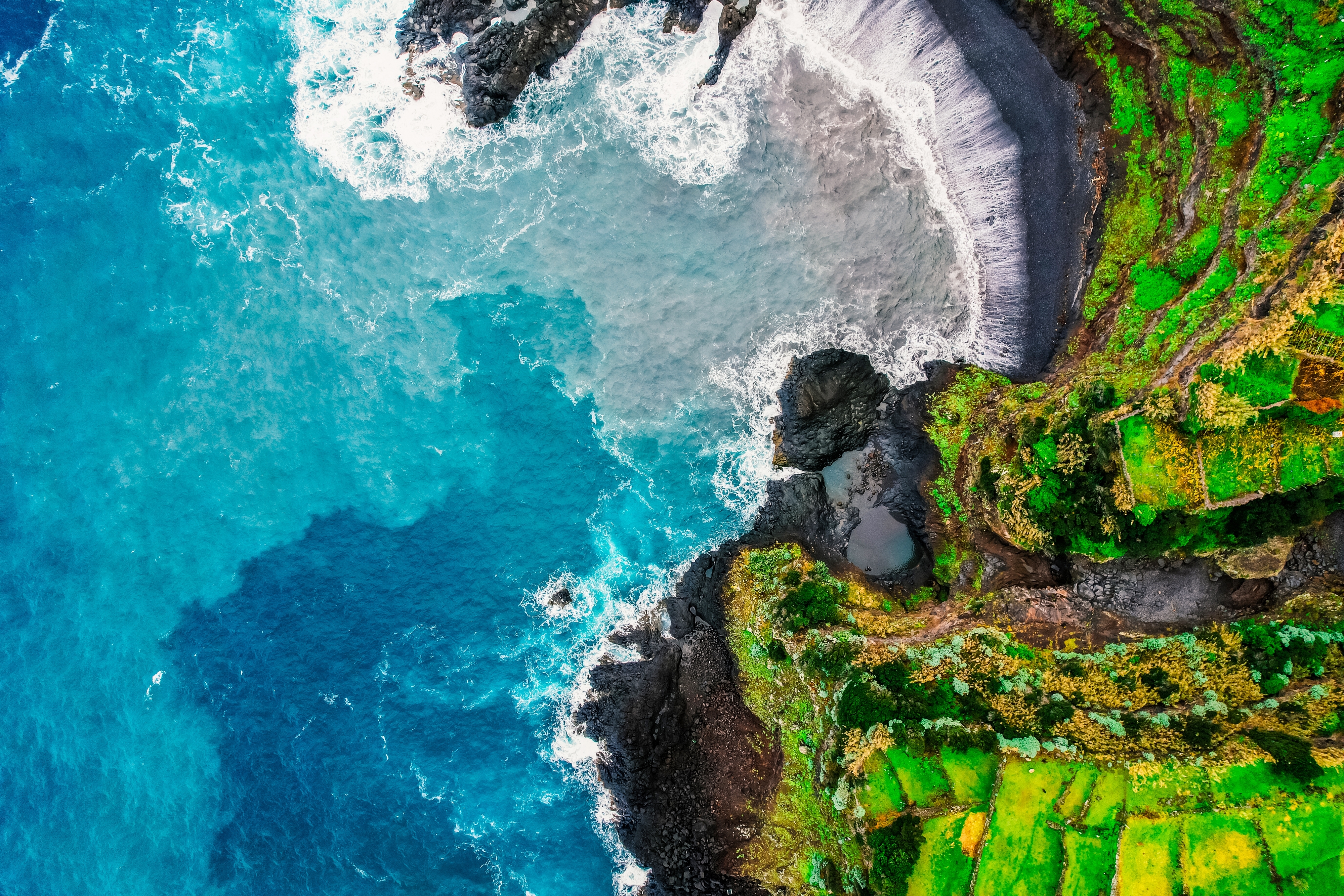 Betagende luftfoto af den vulkanske kyst ved Seixal på Madeira med naturlig svømmepool og Atlanterhavets bølger