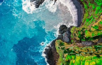 Betagende luftfoto af den vulkanske kyst ved Seixal på Madeira med naturlig svømmepool og Atlanterhavets bølger