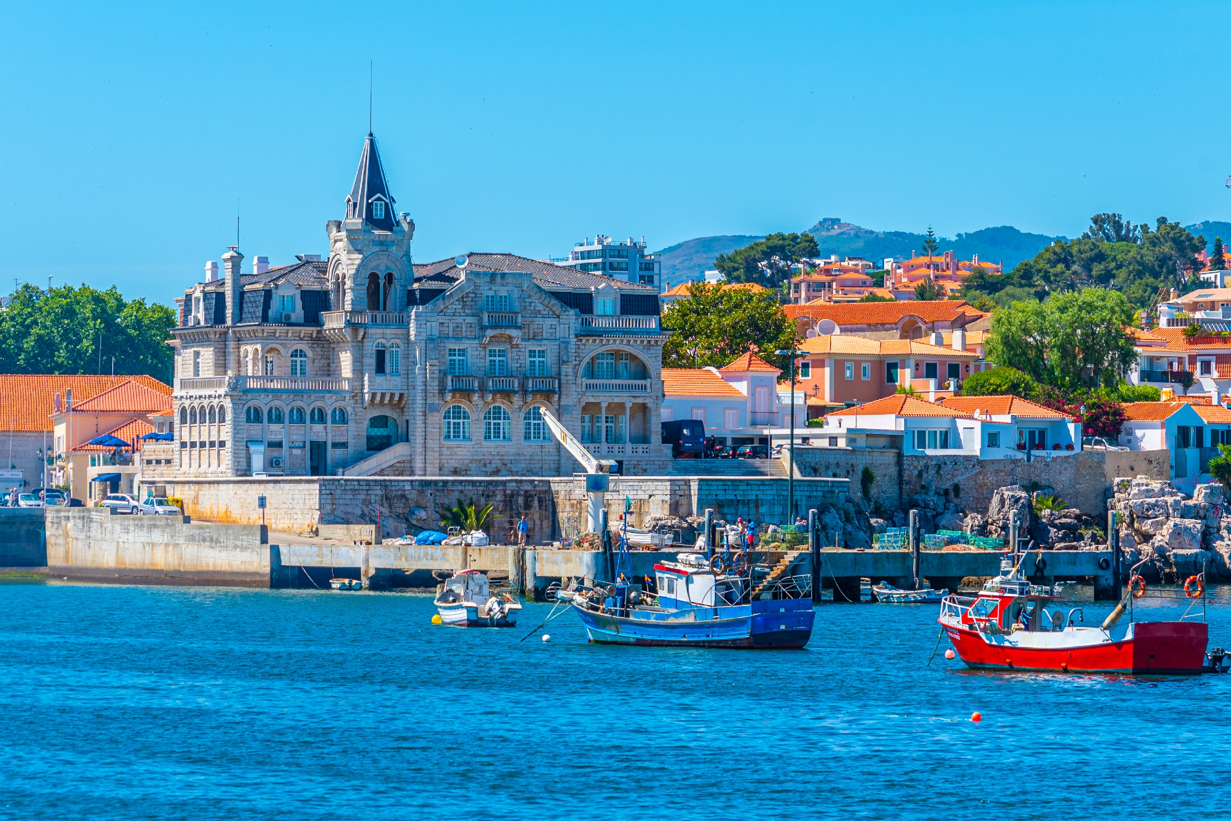 Seixas-paladset ved havnen i Cascais, Portugal, med farverige fiskerbåde på det blå atlanterhav