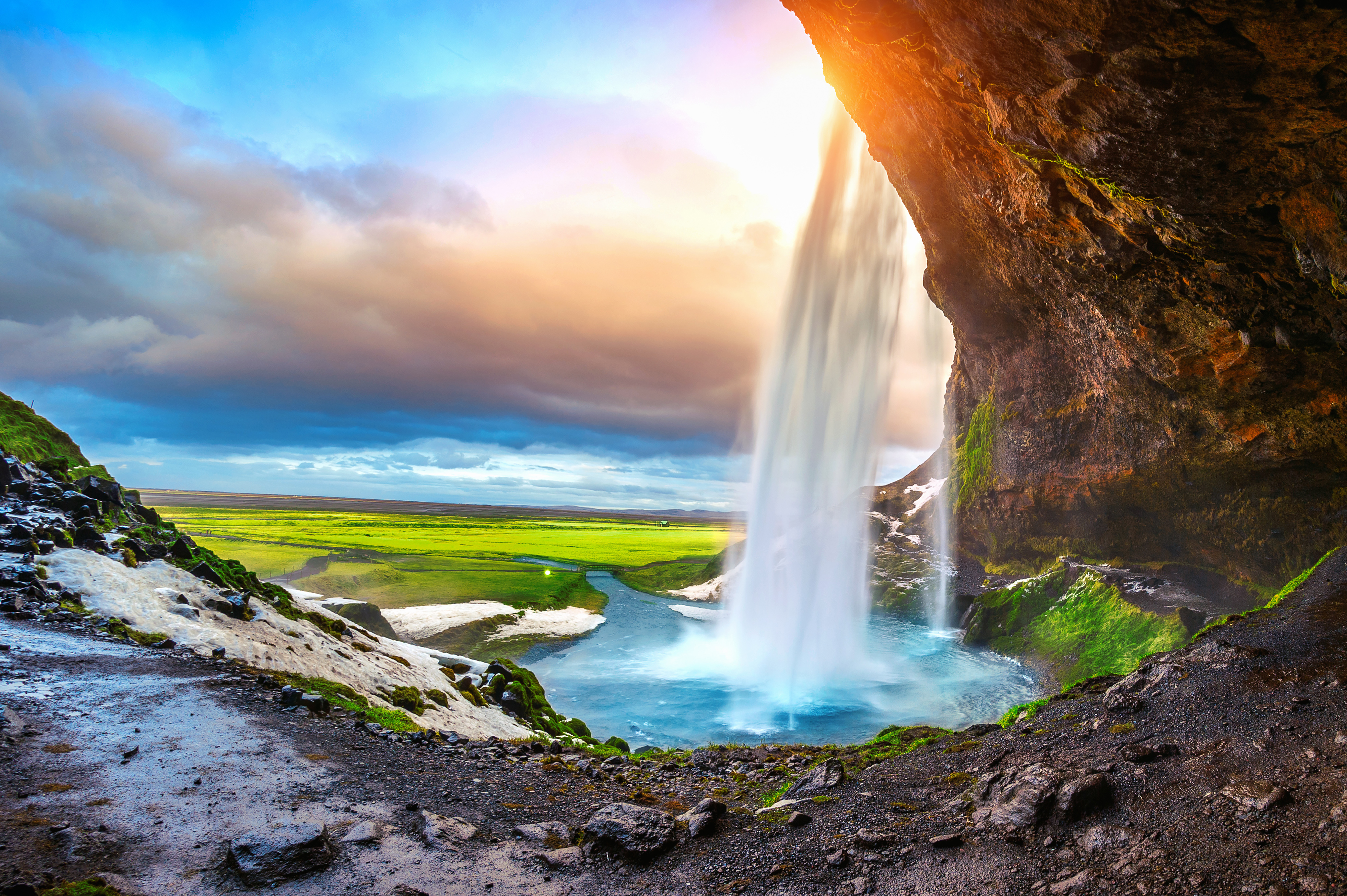 Betagende Seljalandsfoss vandfald badet i gyldent solnedgangslys med frodig grøn vegetation i det sydlige Island