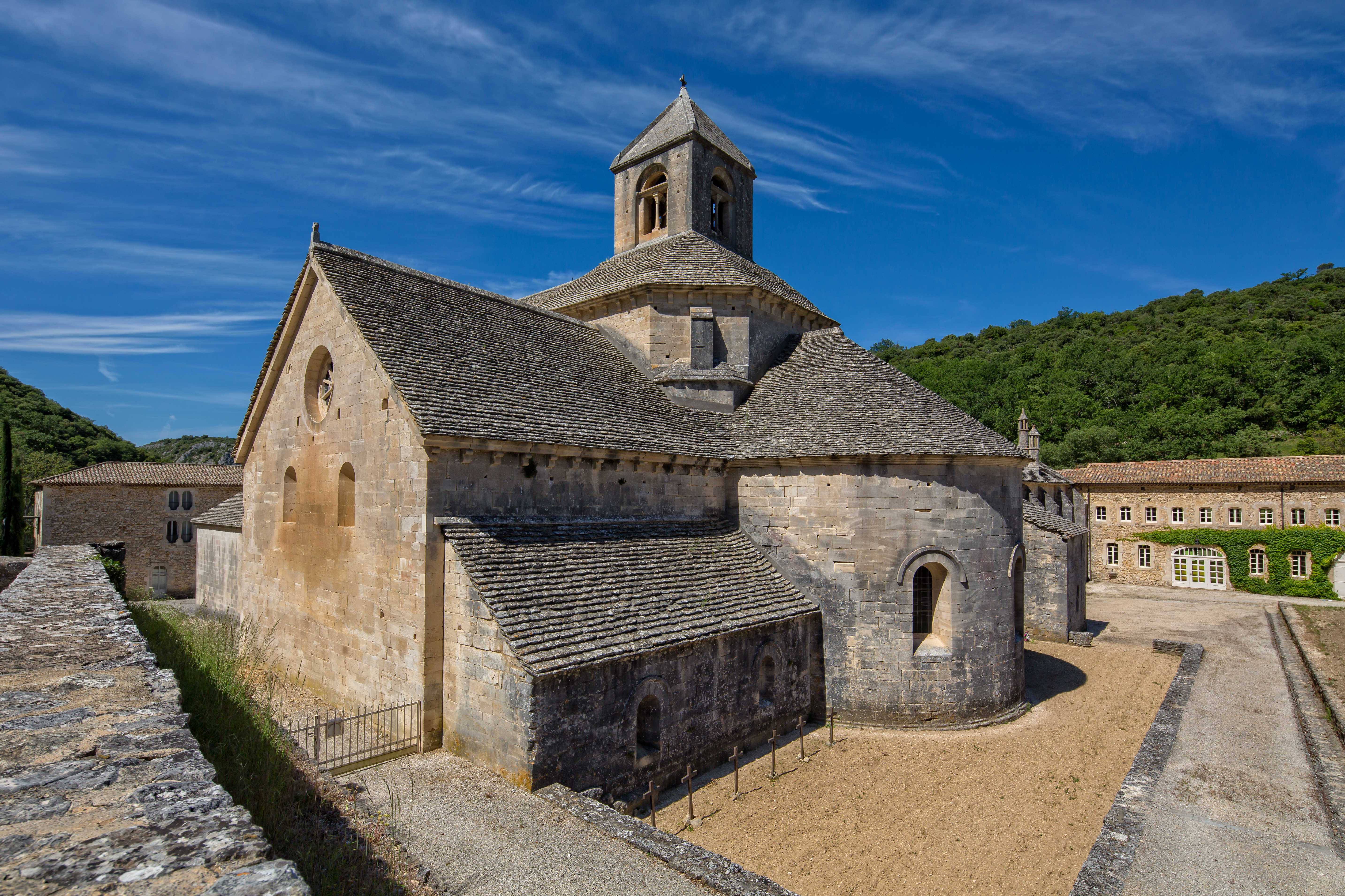 Det historiske cistercienserkloster Abbaye de Sénanque nær landsbyen Gordes i Provence, Frankrig, med smukt romansk stenarkitektur og klokketårn omgivet af grønne bakker