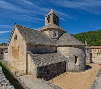 Det historiske cistercienserkloster Abbaye de Sénanque nær landsbyen Gordes i Provence, Frankrig, med smukt romansk stenarkitektur og klokketårn omgivet af grønne bakker