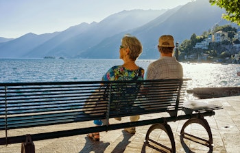 Ældre par nyder udsigten fra en bænk på promenaden i luksuriøse Ascona ved Lago Maggiore i det schweiziske Ticino