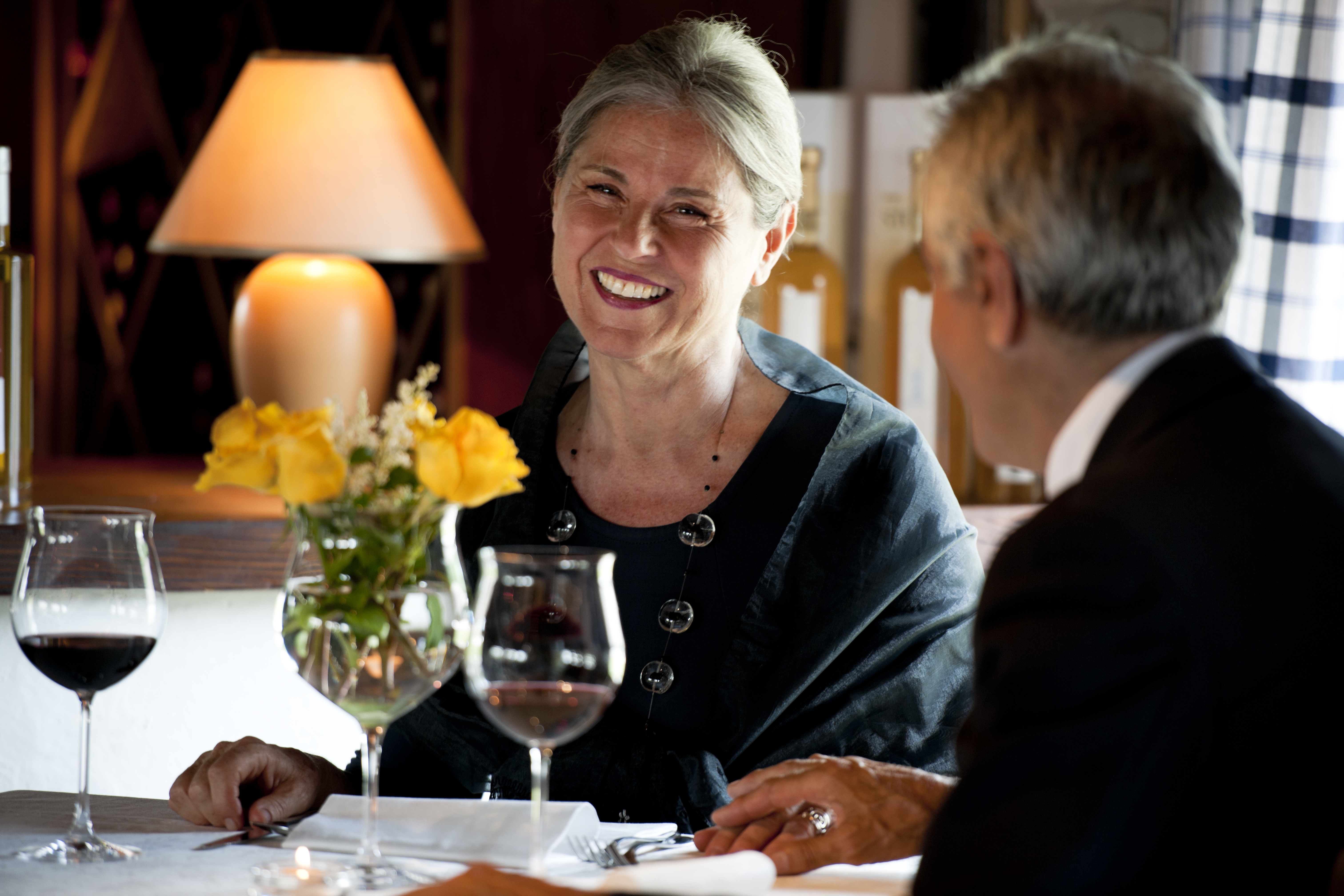 Ældre par nyder romantisk middag med vin på restaurant, smiler til hinanden