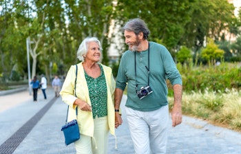 Ældre par nyder en romantisk spadseretur hånd i hånd i Madrid under deres ferie i Spanien