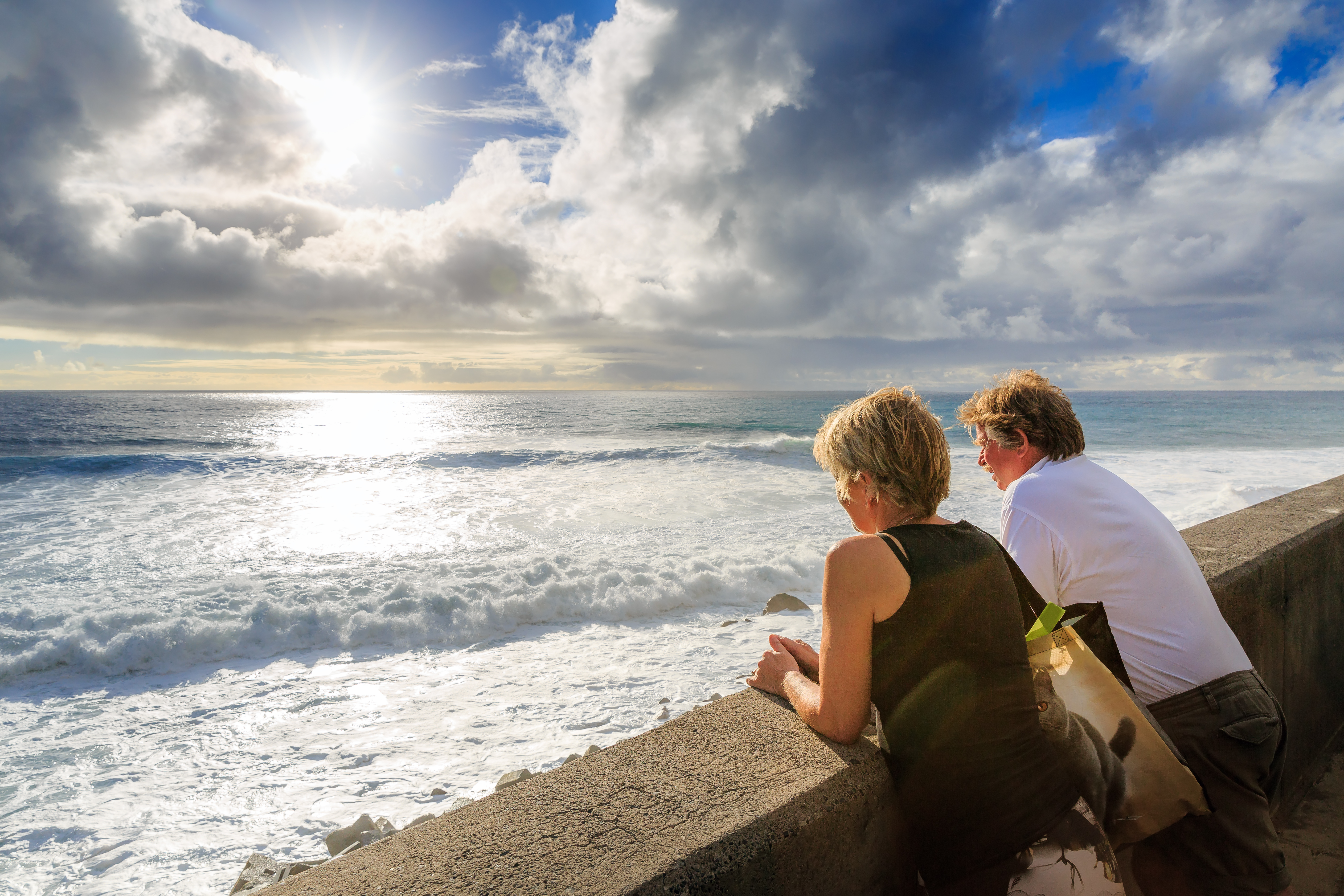 Ældre par nyder romantisk solnedgang ved Atlanterhavets kyst på Madeira, perfekt til en afslappende sommerferie