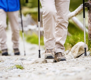 Nærbillede af et senior-pars ben og vandrestøvler på vandretur i bjergene, der viser en aktiv og sund livsstil