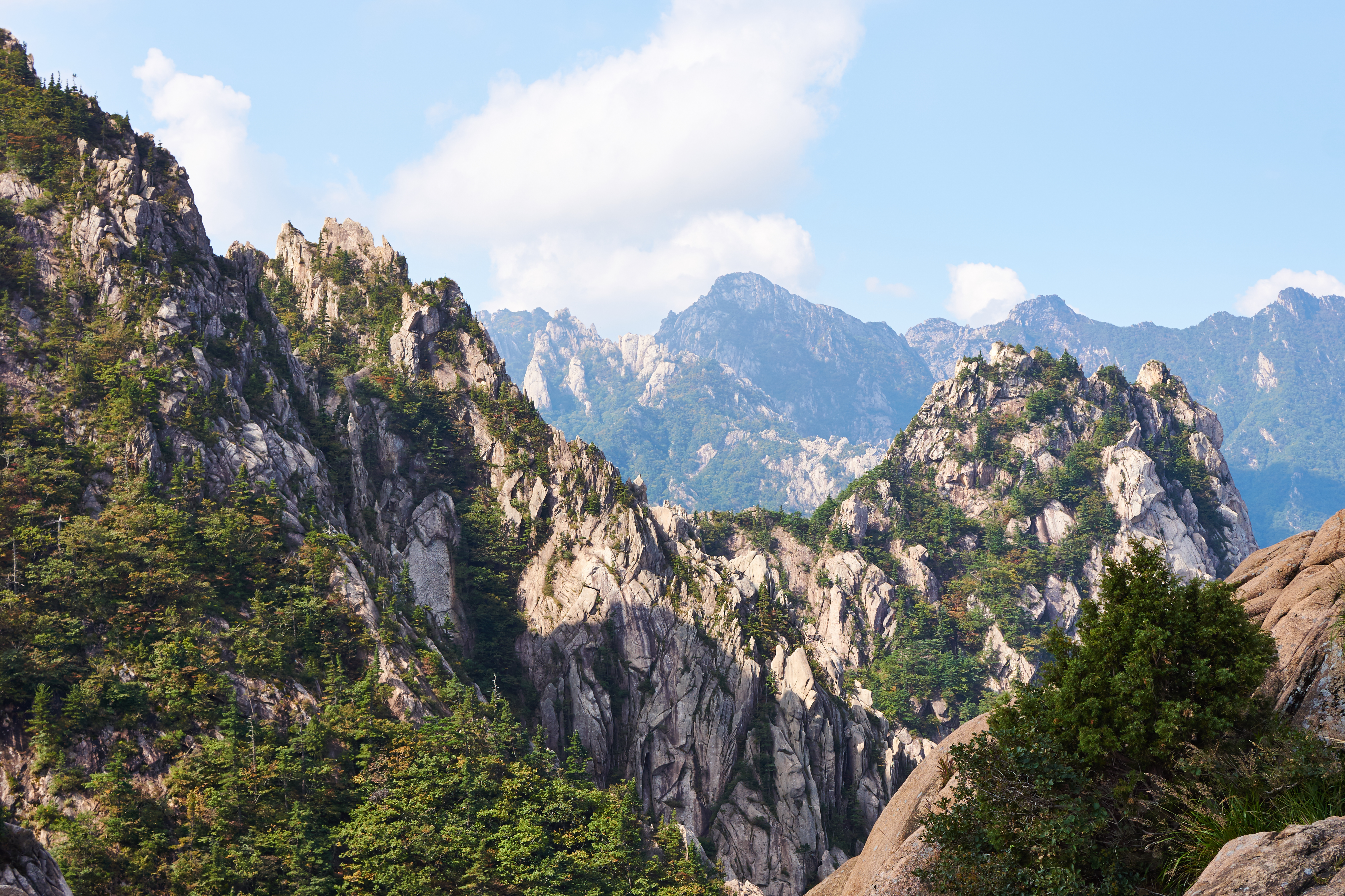 Vandrere nyder den imponerende udsigt fra granittoppen af Seoraksan-bjerget i Sydkorea, omgivet af dramatiske klippeformationer og skovklædte bjerge