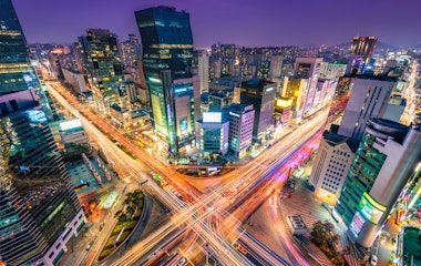 Nattetrafik med lysspor gennem et travlt vejkryds i Gangnam-distriktet i Seoul, Sydkorea