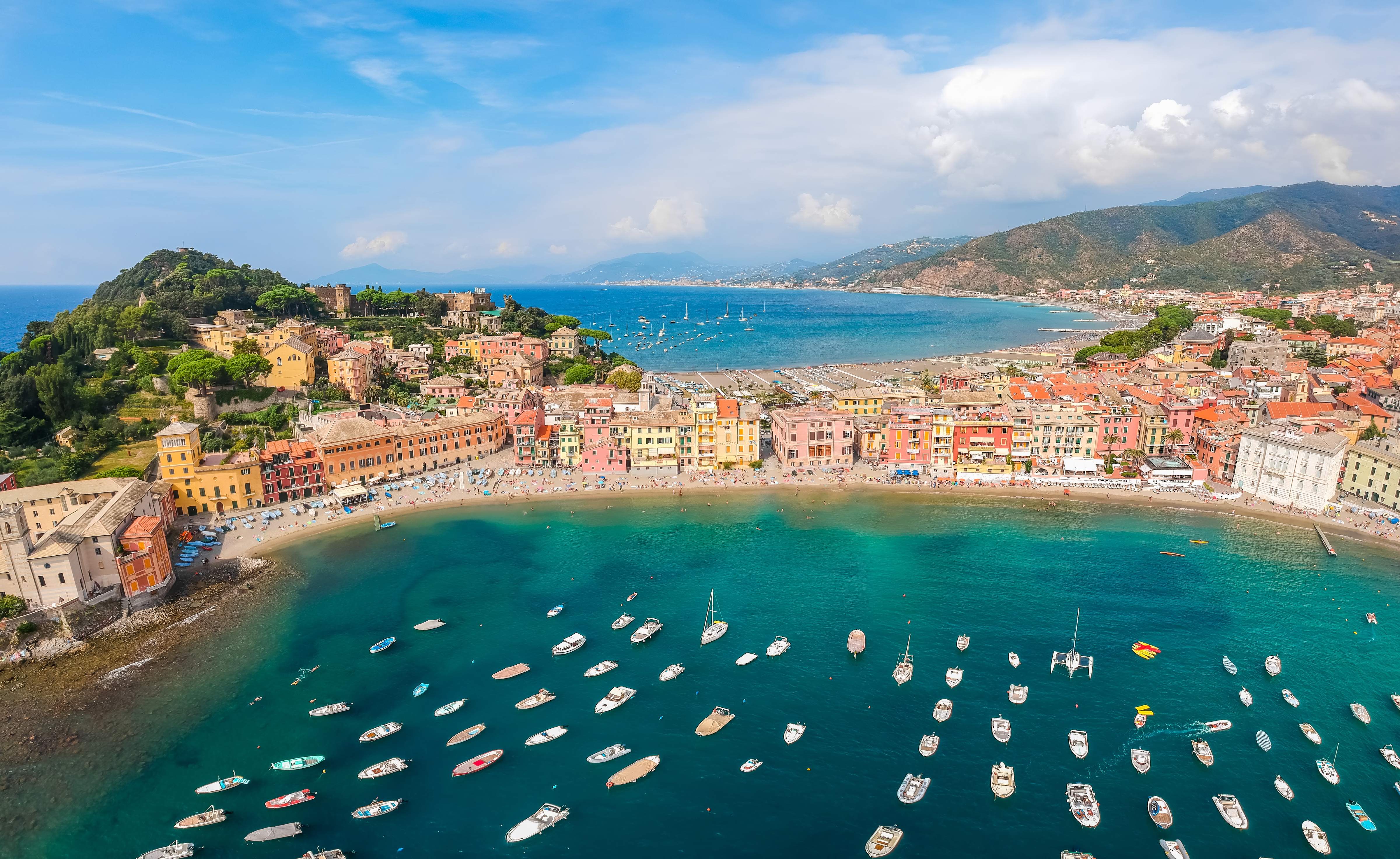 Luftfoto af den maleriske kystby Sestri Levante i Ligurien med turkisblåt vand, farverige huse og små både i den idylliske bugt