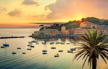 Kystby Sestri Levante i Italien ved solnedgang med både og palmetræ.