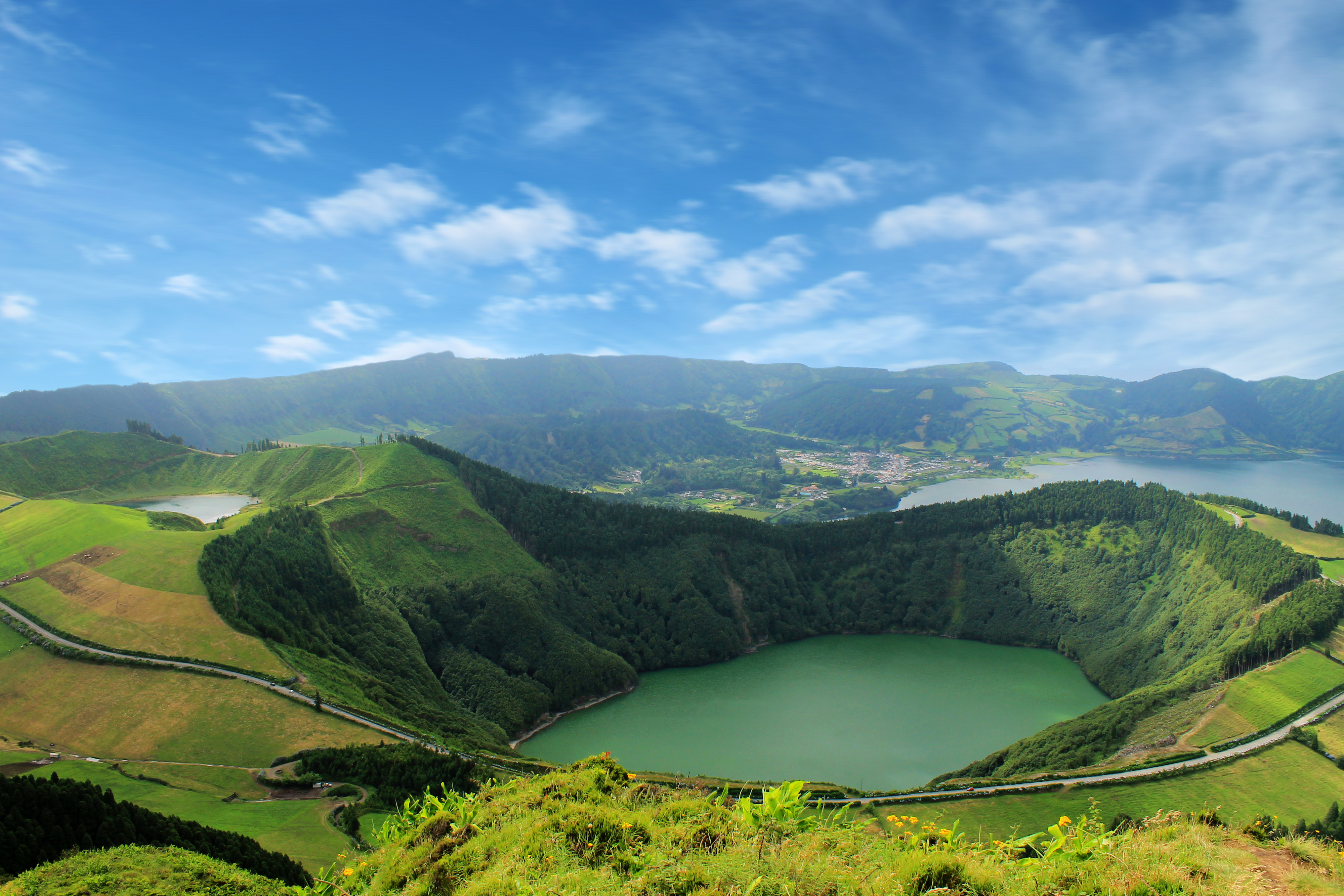 Betagende udsigt over den smaragdgrønne kratersø ved Sete Cidades på São Miguel i Azorerne, Portugal med frodige bjerge og blå himmel