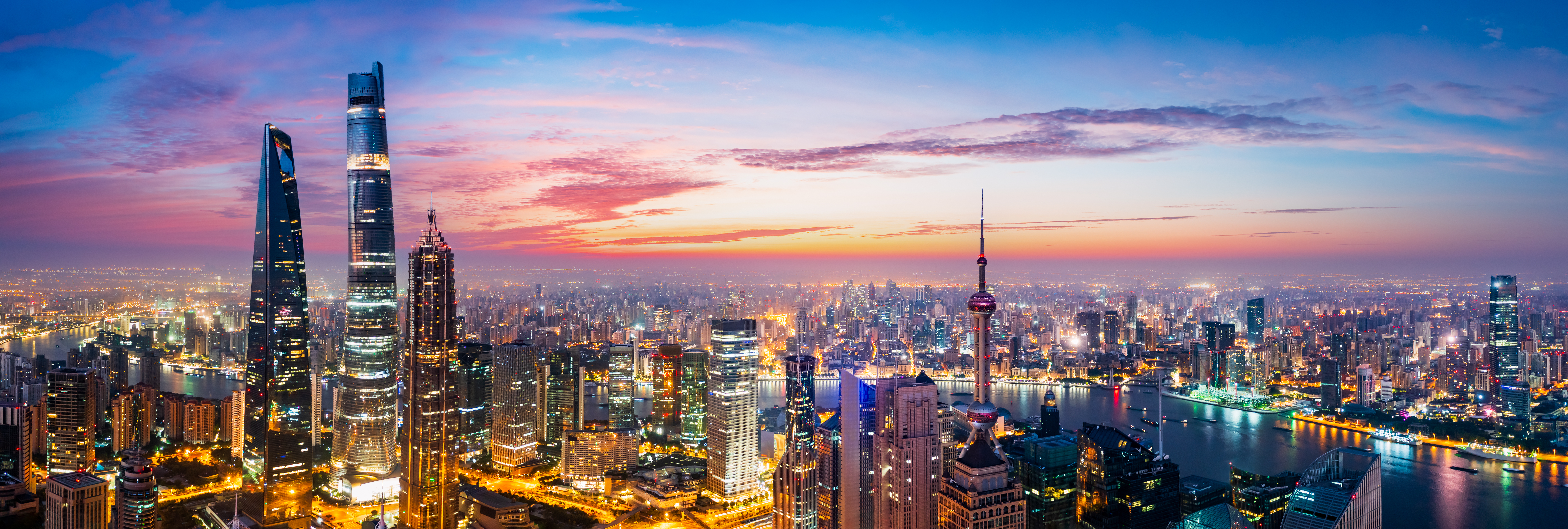 Flot udsigt over Shanghais skyline ved solnedgang med Oriental Pearl Tower og moderne skyskrabere