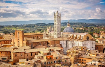 Betagende luftudsigt over Siena Domkirke med dens karakteristiske sort-hvide marmorfacade, der dominerer den middelalderlige bymidte i Toscana, Italien