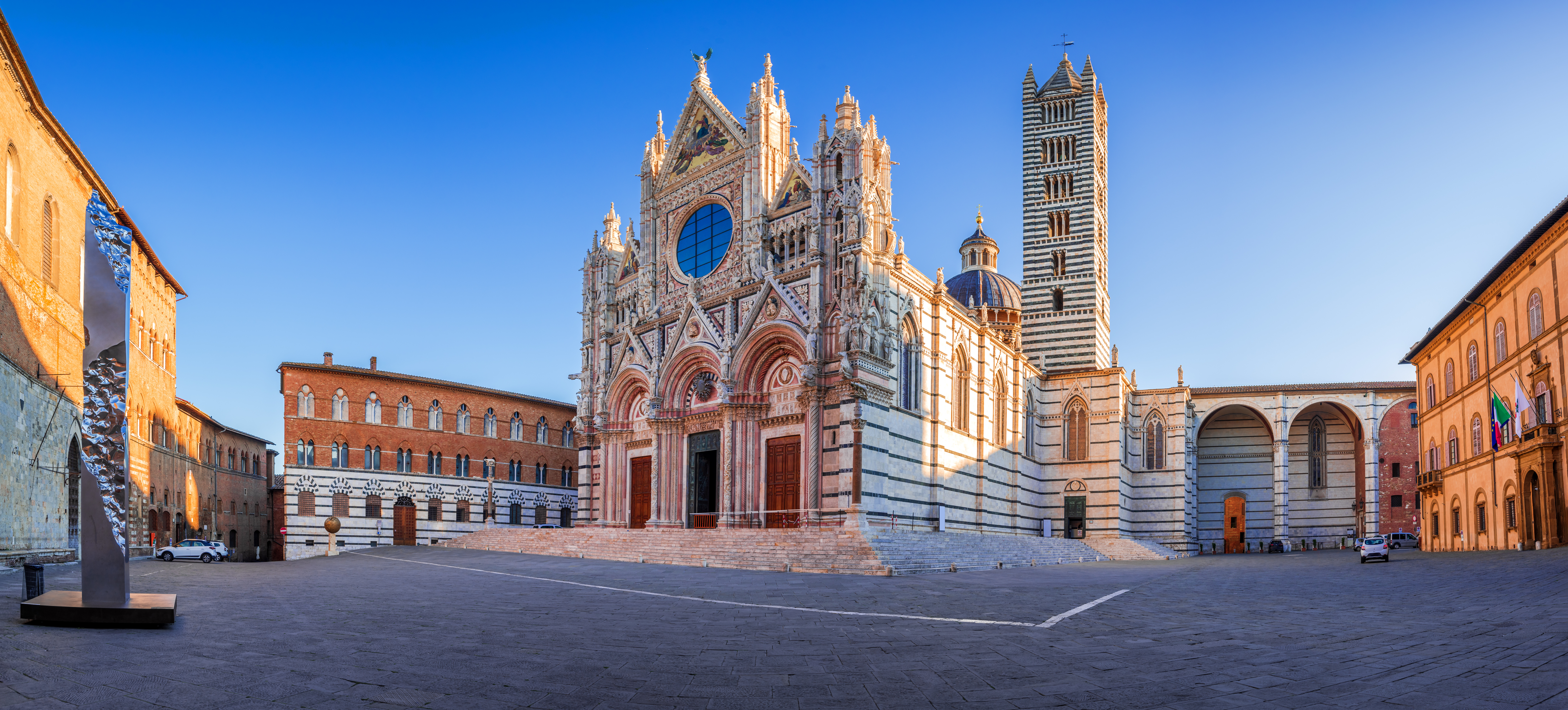 Panoramaudsigt over Sienas smukke domkirke Duomo di Siena med gotisk facade og stribet klokketårn i solopgang, Toscana, Italien