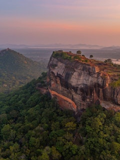 Betagende luftfoto af Sigiriya klippefæstning ved solopgang omgivet af frodig jungle i Sri Lanka, et UNESCO verdensarvssted