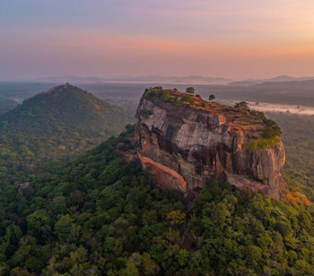 Betagende luftfoto af Sigiriya klippefæstning ved solopgang omgivet af frodig jungle i Sri Lanka, et UNESCO verdensarvssted