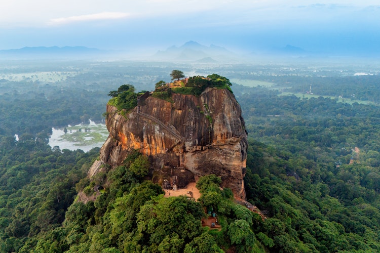 Sigiriya klippeborgen i morgenlys omgivet af frodig grøn vegetation og dis i Sri Lanka, et UNESCO verdensarvsted