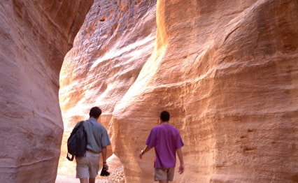 Turister vandrer gennem den smalle Siq-kløft, den dramatiske indgangspassage til den gamle by Petra, UNESCO verdensarvssted i Jordan