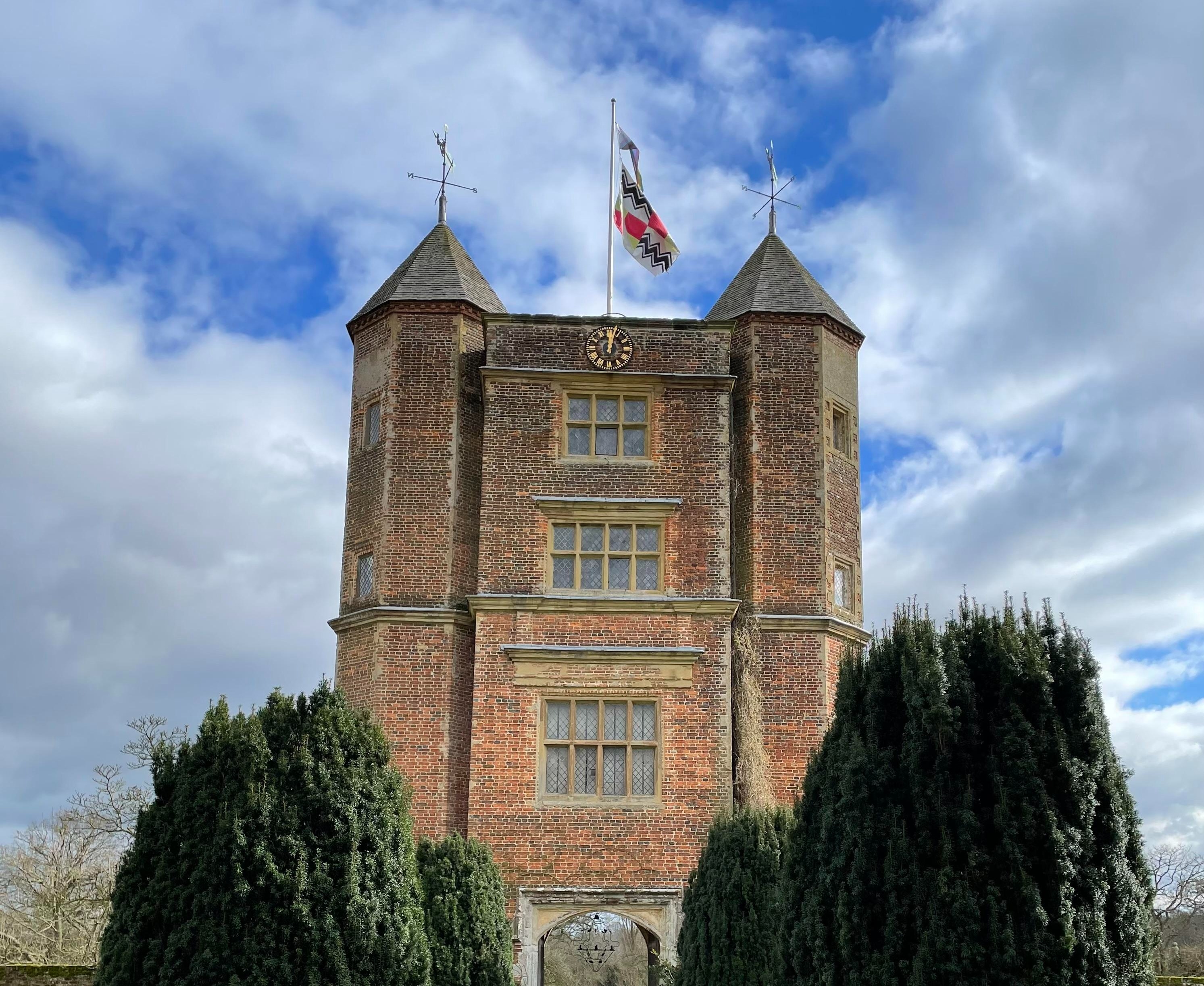 Sissinghurst Castle Tower i Kent, England, med velklippede cyprestræer langs en stenet sti der fører gennem en bue ind i den berømte have