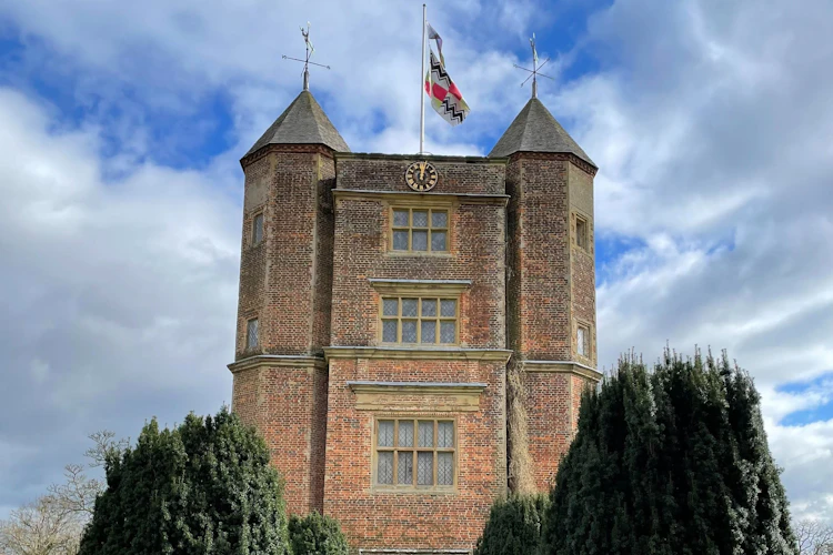 Sissinghurst Castle Tower i Kent, England, med velklippede cyprestræer langs en stenet sti der fører gennem en bue ind i den berømte have