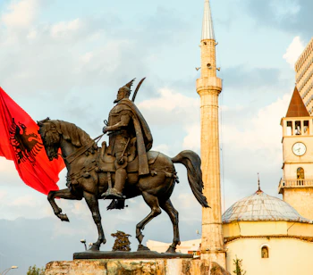 Skanderbeg monumentet med det albanske flag i Tiranas centrum, med Et'hem Bey moskeen og klokketårnet i baggrunden