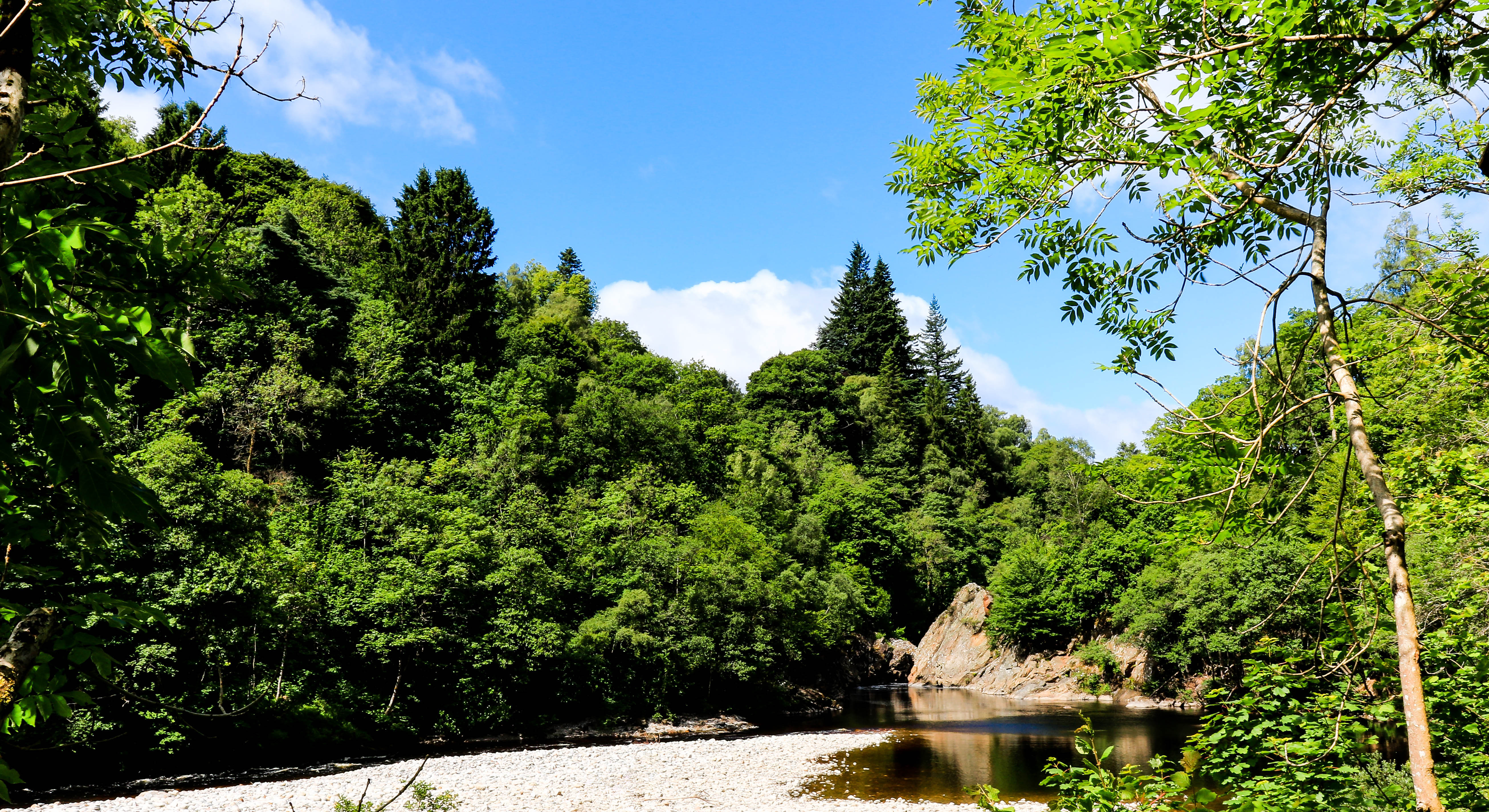 Naturskøn River Garry der flyder gennem grøn skov i Killiecrankie, Skotland på en klar sommerdag