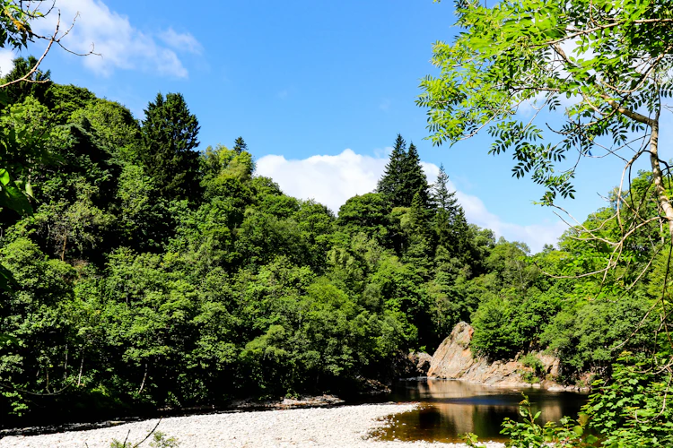 Naturskøn River Garry der flyder gennem grøn skov i Killiecrankie, Skotland på en klar sommerdag