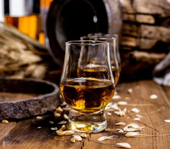 Glas med skotsk whisky på træbord med fade og flaske - whisky smagning på rejse