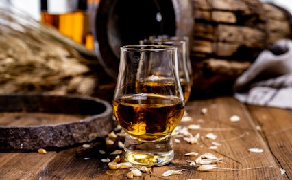 Glas med skotsk whisky på træbord med fade og flaske - whisky smagning på rejse