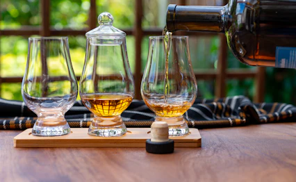 Traditionelle skotske whisky smageglas med gyldne single malt i historisk skotsk hus