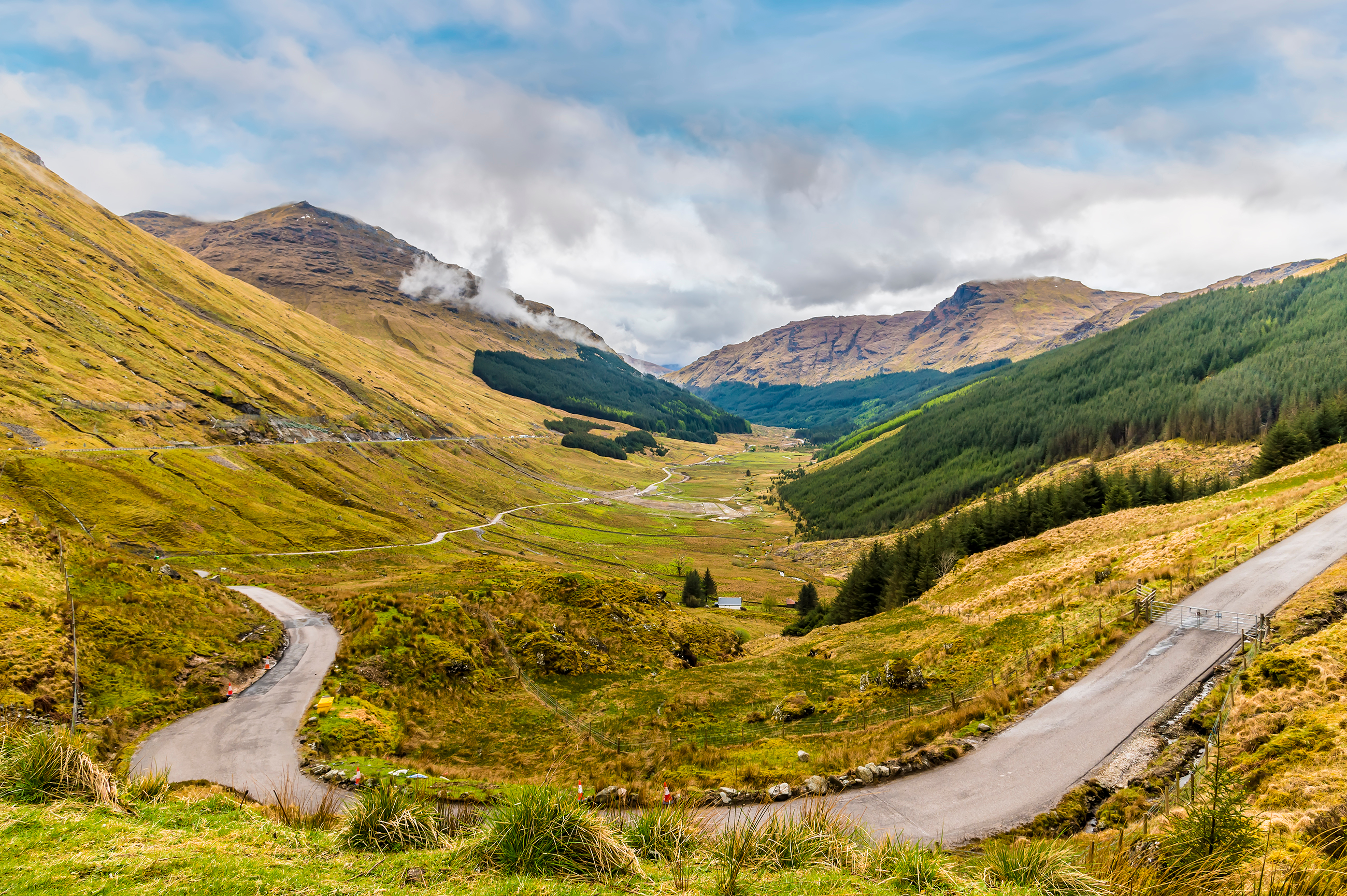 Smukt skotsk højlandslandskab med snoet vej gennem grønne dale og bjerge
