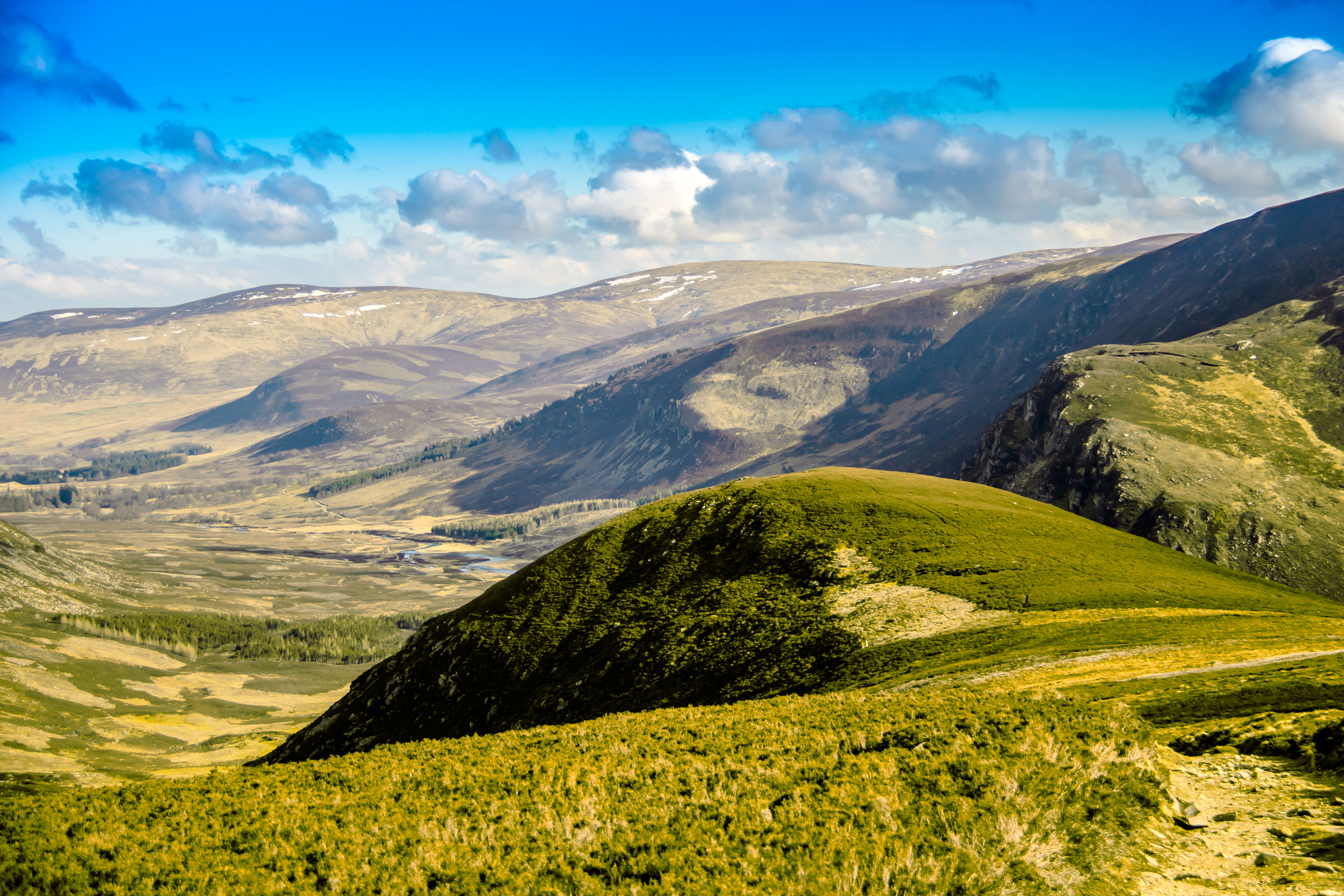 Smuk udsigt over de skotske højlande med grønne bakker og dramatiske dale i Cairngorms Nationalpark