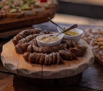 Traditionel slovensk Kranjska klobasa pølse serveret i skiver med sennep på en tallerken, typisk bjergmad fra Slovenien