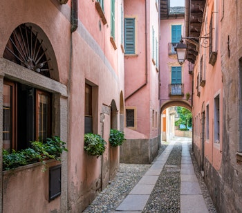 Charmerende smal gade med terracotta-farvede bygninger i den historiske by Orta San Giulio i Norditalien