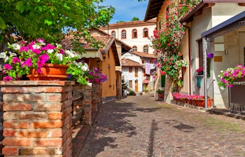Malerisk brostensbelagt gade med blomsterdekorerede huse i vinbyen Barolo, Piemonte i Norditalien