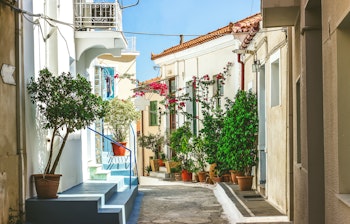 Snævre gader med hvide huse og blomster i Neorio by, Poros ø, Grækenland.