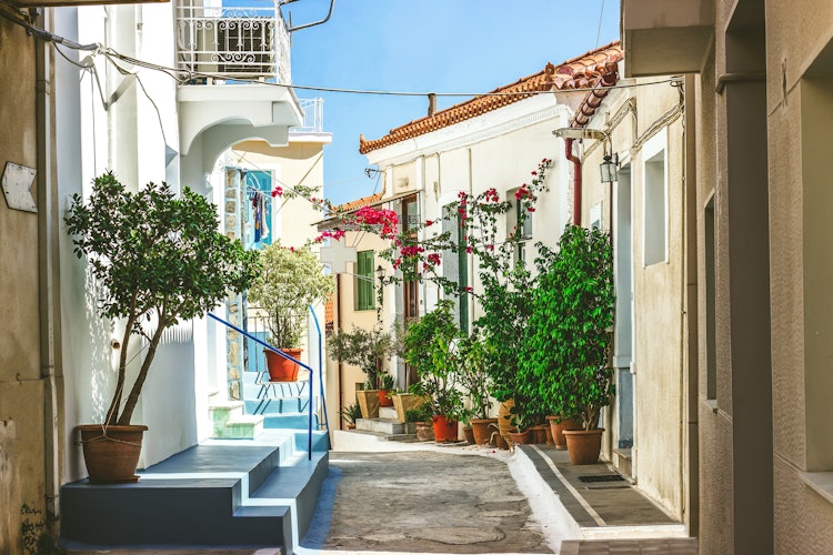Snævre gader med hvide huse og blomster i Neorio by, Poros ø, Grækenland.