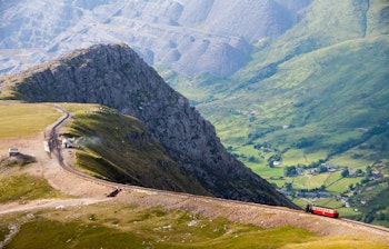 Historisk tog på Snowdon bjergbane med udsigt over Llanberis-dalen og Dinorwig skiferbrud i Snowdonia Nationalpark, Wales