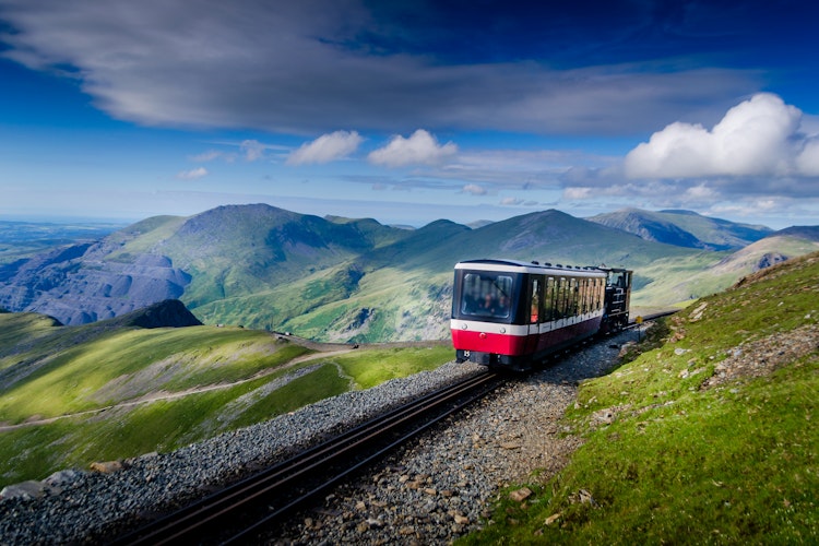 Snowdon bjergtog kører gennem grønne bjerglandskaber i Wales Snowdonia Nationalpark