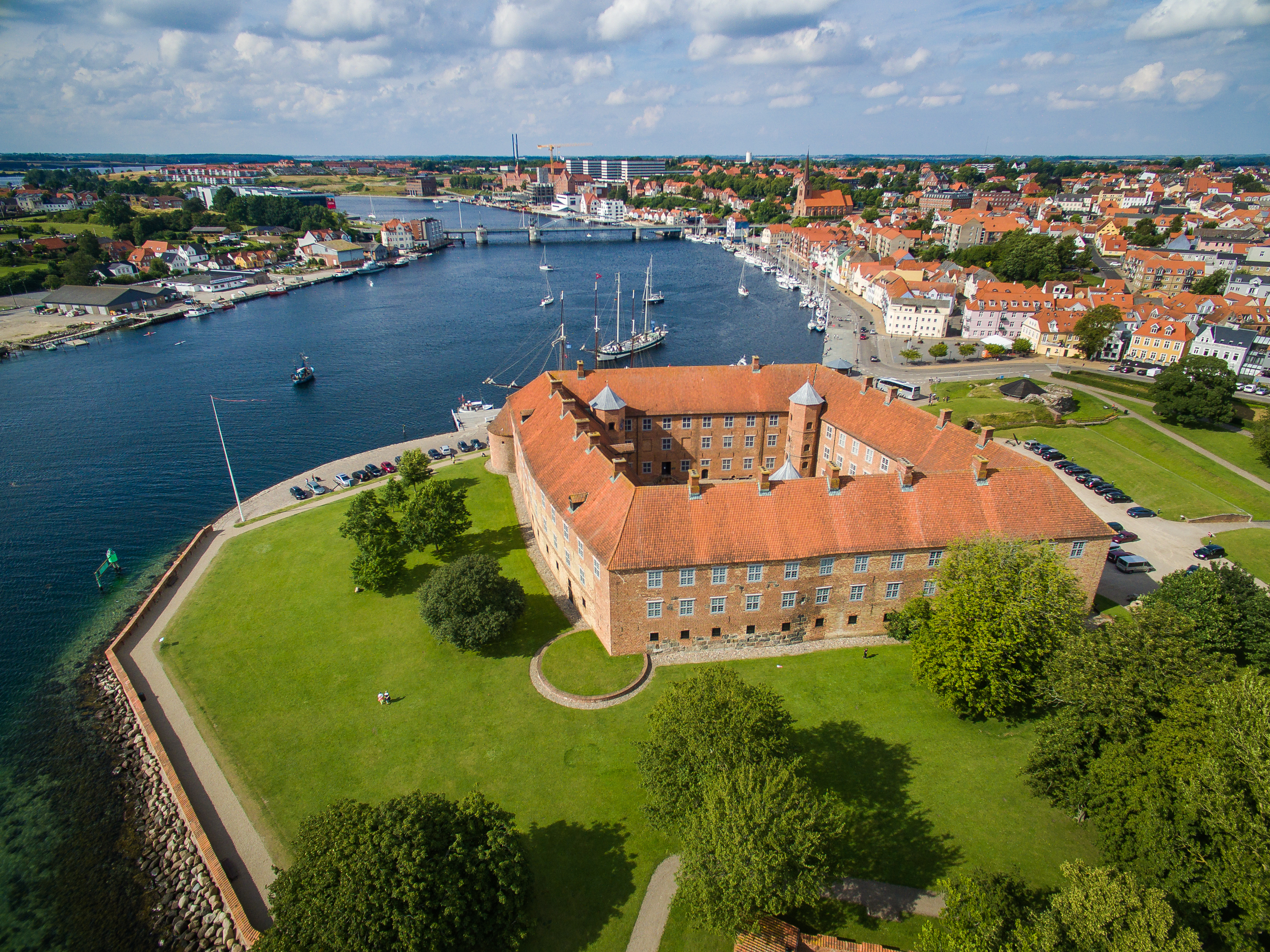 Imponerende luftfoto af det historiske Sønderborg Slot ved vandet med udsigt over byen og havnen i Sønderjylland