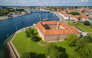 Imponerende luftfoto af det historiske Sønderborg Slot ved vandet med udsigt over byen og havnen i Sønderjylland