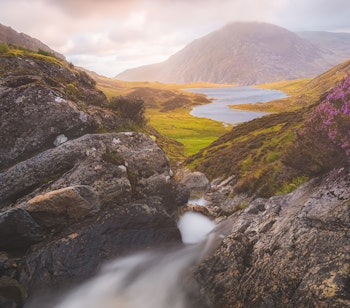 Betagende solnedgang over Llyn Idwal søen i Snowdonia Nationalpark med dramatiske bjerge og gyldent lys under vores rundrejse i Wales