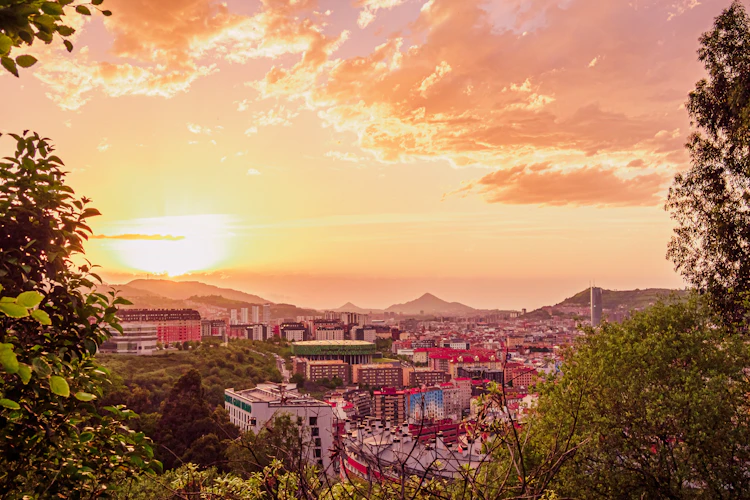 Smuk solnedgang over Bilbao by i Baskerland med gyldent lys og bjerge i baggrunden