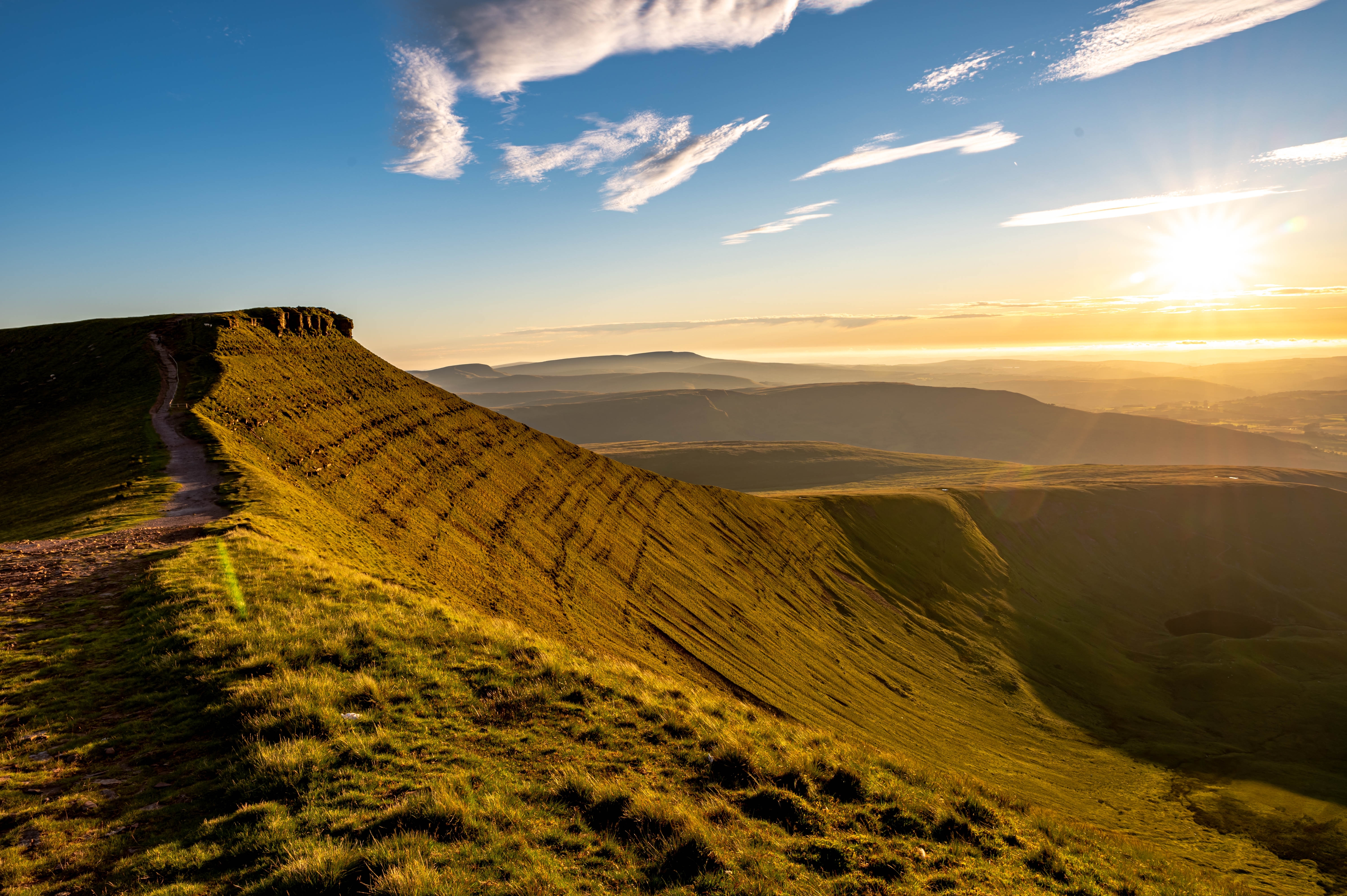 Spektakulær solnedgang over Pen y Fan bjergtop i Brecon Beacons Nationalpark, Sydwales, med vandrerstier og dramatisk landskab